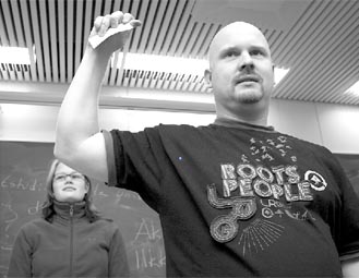 Kulttuurisihteeri Matti Huhta nostaa uuden puheenjohtajan nimen edustajiston kokouksessa. Arvontamaljaa pitelee edustajiston puheenjohtaja Leena Reinikainen. Kuva: Juhani Saarinen